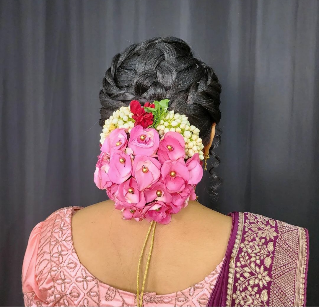 Braided updo finished with pink roses and jasmine styled at Prayosha Salon
